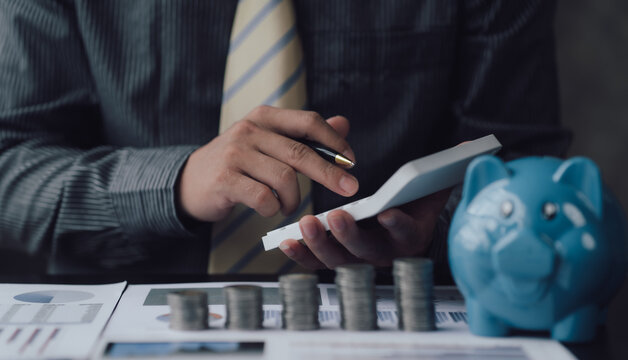 business man holding down a friend calculator to calculate savings Ideas for saving money, taxes, retirement money