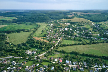 Fototapeta na wymiar Aerial landscape view of green cultivated agricultural fields with growing crops and distant village houses