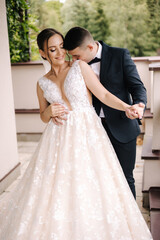 Portrait of newlyweds stand on balcony and dreaming. Handsome groom and beautiful bride on their wedding day