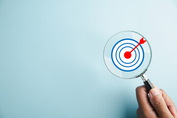 The magnifier glass centers on a target board, showcasing the importance of business objectives, it...