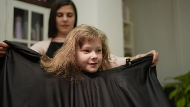 The hairdresser wraps the client with a cape