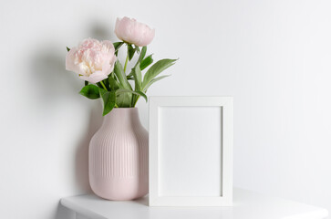 White photo frame mockup in white interior with peony flowers, blank frame mockup with copy space