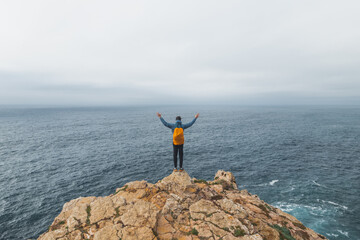 Black-haired adventurer stands at the end of Cape Cabo de Sao Vicente in the southwest of Portugal...
