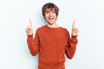 Young caucasian man isolated on blue background indicates with both fore fingers up showing a blank...
