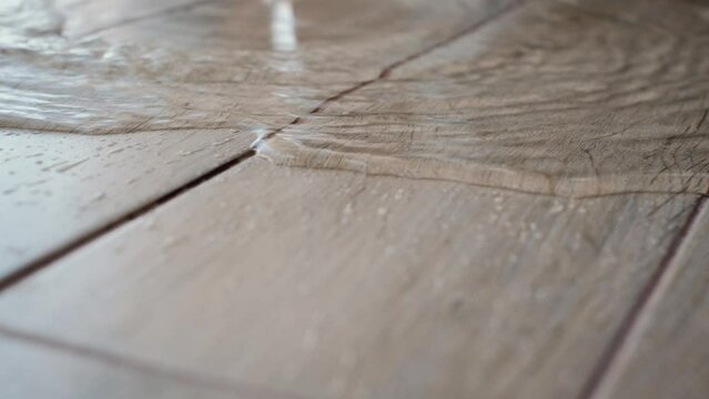 Running water drips and spreads across the floor, close-up. Flood