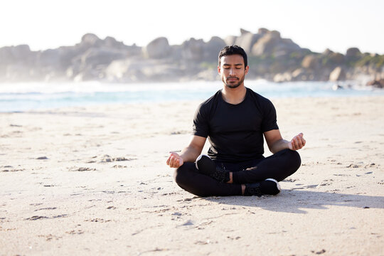Freedom, man sitting on the beach and meditation for peace of mind during summer. Relax or harmony meditating, mental health and male person on the sea sand for health wellness in fresh air outdoors