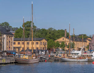 Fototapeta na wymiar Old sailing boats moored at a pier on the maritime island Skeppsholmen, a sunny summer day in Stockholm