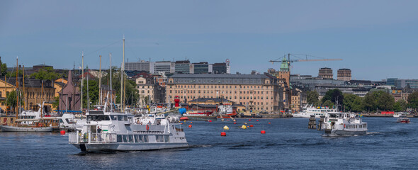 Ferries in the bay Ladugårdslandsviken, the pier Strandvägen with hotels apartments and boats, a sunny summer day in Stockholm