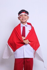 Indonesian elementary student wearing white and red uniform holding Indonesian flag. Celebrating...