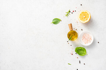 Various herbs and spices, oil in glass bowl and half of lemon on a white concrete background....