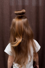 Naklejka premium Girl's hairstyle braided in a braid fixed with a blue elastic band close-up. Hair styling is done with hairpins and an elastic band. Only the back of the head with a haircut