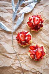 Beautiful cupcakes with strawberries along with a branch on kraft paper