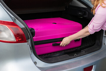 Packing for travel, moving, Suitcase transportation, woman putting suitcase in car trunk