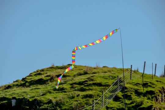 Long and thin rainbow patterned coloured flag flying in the wind. Streaming multicoloured flag near a beach. 