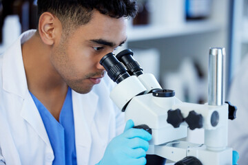 Science, futuristic and a man with microscope in a lab for medical research and analysis. Serious,...