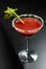 Bloody Mary cocktail with celery on a black background.
