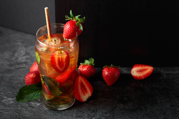 Iced tea or a summer refreshing drink with ice, mint, and strawberries.