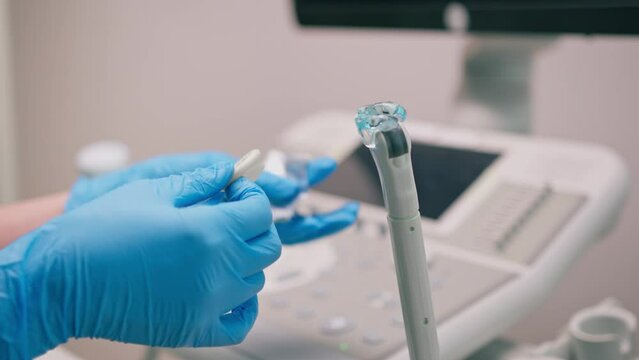 Gynecologist applies gel on transvaginal ultrasound to diagnose patient in clinic medicine and health concept close-up gel on devices