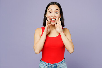 Fototapeta premium Young woman of Asian ethnicity wear casual clothes red tank shirt scream sharing hot news about sales discount with hands near mouth isolated on plain pastel light purple background studio portrait.