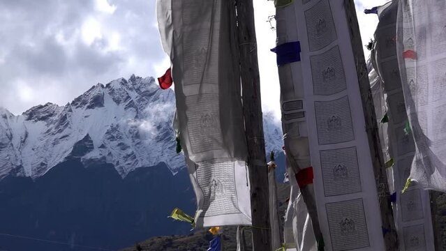 colorful tibetan prayer flags on high posts with himalaya mountain 
snow covered peaks in background, Slow motion, 2023
