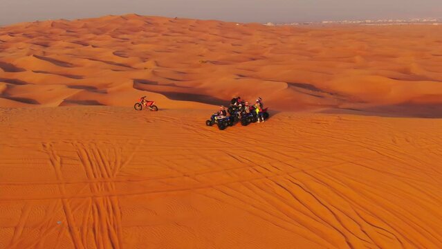 The drone flies to the quadra in cycles standing on sand dunes in the desert of the United Arab Emirates