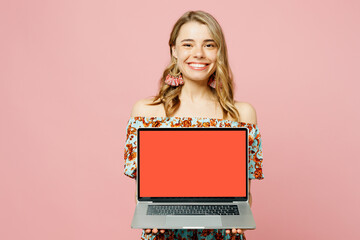 Naklejka premium Young blonde IT woman wear summer casual clothes hold use work on laptop pc computer with blank screen workspace area isolated on plain pastel light pink background studio portrait. Lifestyle concept.