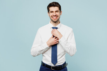 Young fun smiling happy cool successful employee business man corporate lawyer wearing classic formal shirt touching tie work in office isolated on plain pastel light blue background studio portrait.