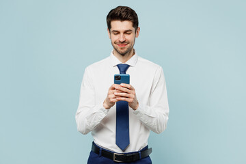 Young successful employee business man corporate lawyer wear classic formal shirt tie work in office hold in hand use mobile cell phone isolated on plain pastel light blue background studio portrait.