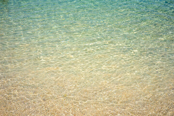 clear turquoise shallow water on white yellow tropical sand beach. Tropical background of paradise water with light reflections.