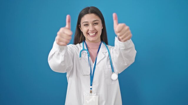 Young beautiful hispanic woman doctor doing thumbs up over isolated blue background