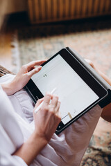 Closeup woman holding in hand digital tablet with stylus in the living room. Concept of technology, connection, communication. Woman using tablet