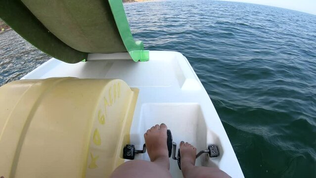 Woman floating on catamaran. Person pedaling with her feet and swimming on catamaran on sea surface with waves on sunny summer day. Active lifestyle recreation leisure sport POV