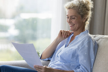 Positive mature senior woman reading legal document, medical insurance, bank agreement, investment...