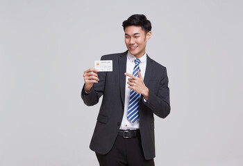 Handsome southeast Asian business man in standing and showing credit card isolated on white studio...
