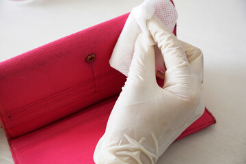Cropped hand erasing leather paint from a purse using alcohol wipe                            