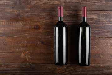 Two bottles of red wine on a wooden background. View from above.