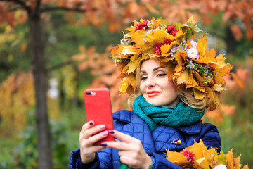 Beautiful young woman posing in the autumn garden wearing a wreath of colorful autumn leaves