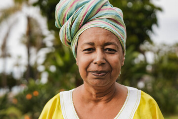 Senior african woman wearing traditional clothes and turban while smiling on camera outdoor