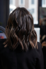 A closeup view of a bunch of shiny curls brown hair.