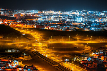 Fototapeta na wymiar Aerial view of the night city of Muscat - the capital of the Sultanate of Oman. Road junctions and houses illuminated at night
