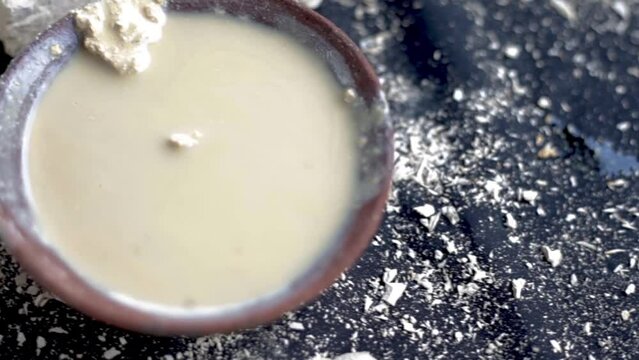 Multani mitti or Fuller's earth on a black surface and its paste in a clay bowl used for face masks and face packs for naturally glowing skin. HD footage in 24FPS.