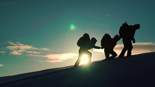 Climbers Man Woman Hand In Hand. Teamwork Business People Partner. Silhouette Of Group Of Tourists, Travelers, Extending Helping Hand To Each Other, Climbing Snowy Slope, Mountains. Teamwork, Business