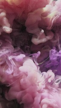 Vertical video. Paint water shot. Color vapor cloud. Opener effect. Pastel purple yellow ink splash glitter dust particles motion on black abstract art background.