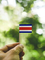 The Flag of Costa Rica which is held in hand at the forest.