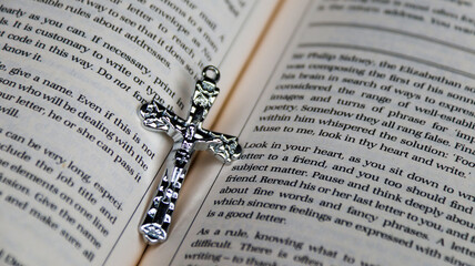 Shiny metal cross on old book to  recall the kindness of Jesus Christ for all of Christian                               