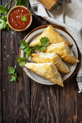 Asian food. Vegetarian samsa (samosas) with tomato sauce on a wooden table. Popular in Indonesia as Risoles Sayur. View from above.