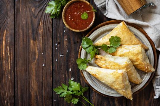 Asian food. Vegetarian samsa (samosas) with tomato sauce on a wooden table. Popular in Indonesia as Risoles Sayur. View from above. Copy space.