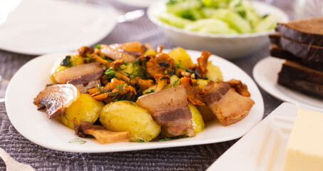 baked potatoes with chanterelles and bacon served with herbs on white plate