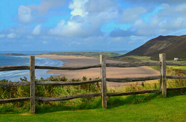 Rhossili beach in Wales, UK with a wooden fence and a lot of clouds