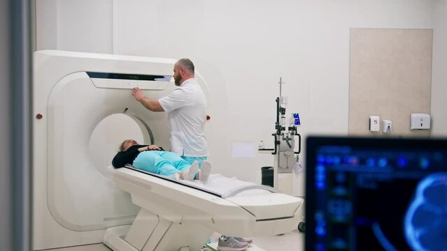 A radiologist performs a computer tomography procedure in a medical clinic A head examination is performed on the patient